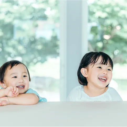 ソファに座る二人の子どもが笑顔