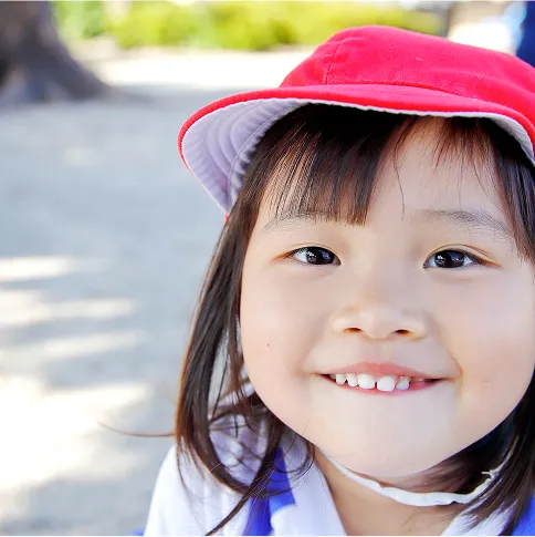 赤い帽子をかぶった笑顔の女の子